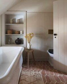 a white bathtub sitting next to a toilet in a bathroom under a slanted ceiling