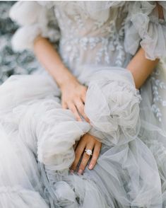 a woman in a white dress is holding her hand on the back of another person's arm