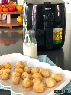 some food is sitting on a plate next to an air fryer and oranges