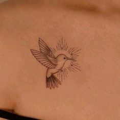 a small bird tattoo on the back of a woman's left shoulder and chest