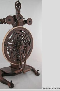 an intricate wooden spinning machine with wheels on it's sides and handles, in front of a white background