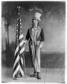 an old black and white photo of a man dressed as uncle lincoln holding the american flag