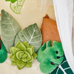 green and brown pillows on a bed with a white drapes over the headboard