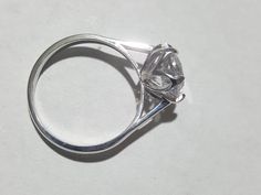 a diamond ring sitting on top of a white surface with the center stone in the middle