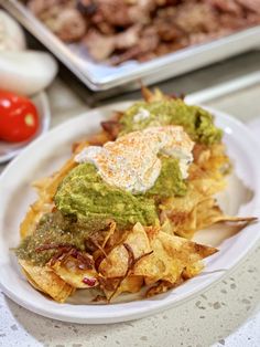 a white plate topped with nachos covered in guacamole and chips