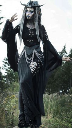 a woman dressed in black with horns and makeup