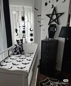 a white crib with black and white decor on the walls, bats and stars