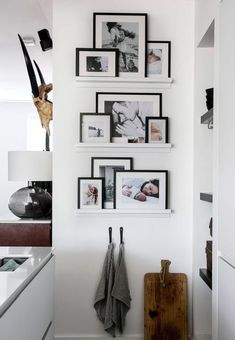 a kitchen with white cabinets and pictures on the wall