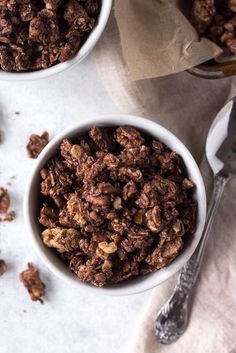 two white bowls filled with granola on top of a table