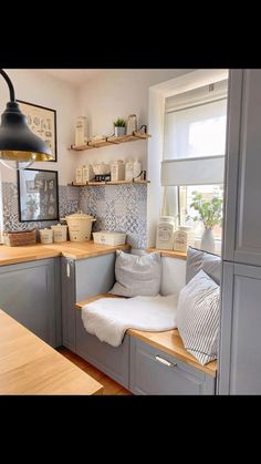 a kitchen with gray cabinets and wooden counter tops next to a white window sill