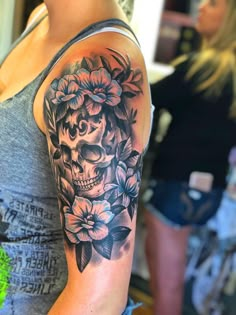 a woman with a skull and flowers tattoo on her arm