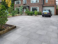 a car is parked in front of a large brick house with trees and shrubs around it