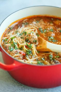 a red pot filled with meat and noodles