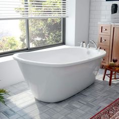 a large white bath tub sitting next to a window