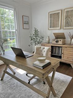 a laptop computer sitting on top of a wooden desk in front of a large window