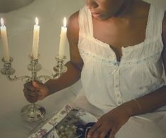 a woman sitting in front of three lit candles