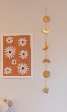 a stuffed animal sitting next to a wall hanging with sun and moon decorations on it