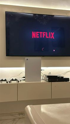 a television that is on top of a table in front of a wall with the netflix logo