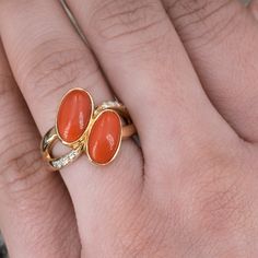 This gorgeous coral ring is centered with two (2), bezel set, oval cabochon cut natural coral. The ring features a split shank design and is accented with eight (8), bead set, round brilliant cut diamonds. The ring measures 18.1mm at the top, rises 5.7mm above the finger, tapering to 2.9mm wide and 1.3mm thick at the base of the shank. "K18 D0.11" is stamped on the inside shank. The ring is currently a size 6.5. Gold Ring Designs, Coral Ring, Coral And Gold, Natural Coral, Bead Set, Split Shank, Ruby Ring, Red Coral, Oval Cabochon