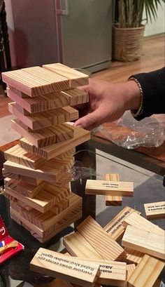 a person stacking wooden blocks on top of each other in front of a glass table