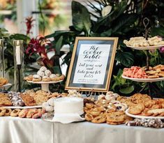 a table filled with cookies and pastries on top of a white cloth covered table