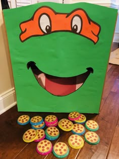 a green bag that has some cupcakes in front of it and a smiling turtle on top