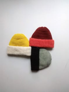 two knitted hats sitting next to each other on top of a white countertop