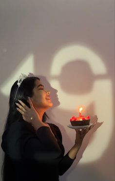 a woman holding a plate with a cake on it in front of the number 50 sign