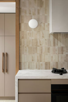 a modern kitchen with beige cabinets and marble counter tops, along with a black stove top oven