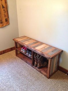 a wooden bench sitting in the corner of a room next to a wall with shoes on it