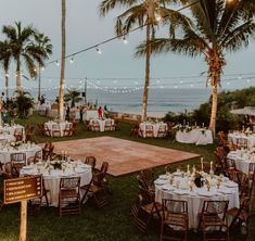 an outdoor wedding reception with tables and chairs set up on the lawn by the ocean