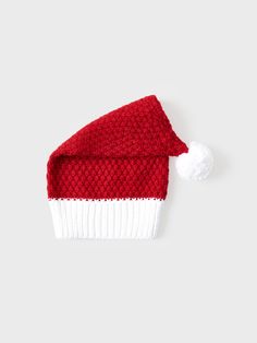 a red and white knitted hat with pom - pom on the side