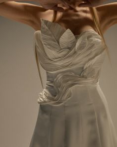 the back of a woman's dress with her hands on her head and arms behind her