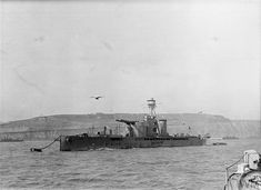 an old photo of a ship in the water with birds flying over it and another boat nearby