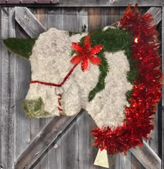 a white stuffed animal laying on top of a wooden floor next to a red tinsel garland