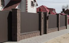 a brick fence and gate in front of a row of houses with red roof tops