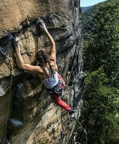 a woman climbing up the side of a cliff