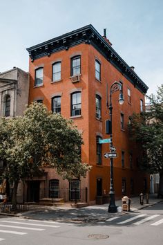 an orange brick building on the corner of a street with trees in front of it