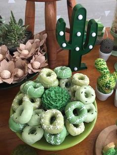 a table topped with green donuts and cactuses next to fake succulents