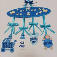 a baby's name and birth date hanging from a blue ribbon on a white wall