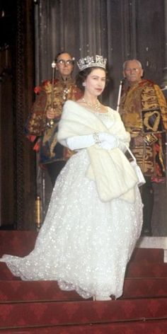 an old photo of a woman in a white dress and tiara with two men standing behind her