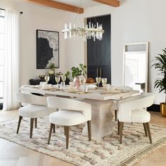 a dining room table with white chairs and a chandelier