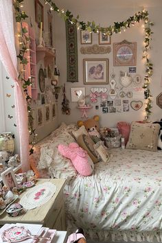 a bedroom decorated in pink and white with lots of pictures on the wall above the bed