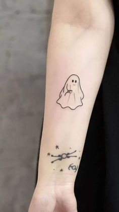 a person with a ghost tattoo on their arm and the words cute written in black ink