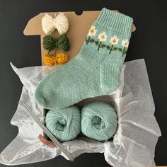 two balls of yarn sitting on top of a table next to some scissors and knitting needles