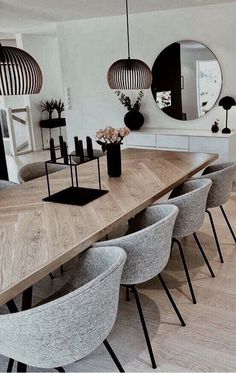 a large wooden table surrounded by chairs in a living room with mirrors on the wall