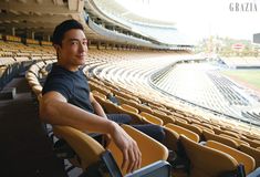 a man is sitting in a stadium with his legs crossed and looking at the camera