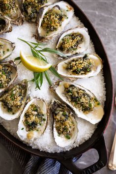 a pan filled with oysters on top of white rice and garnished with herbs