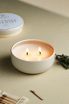 two candles sitting on top of a table next to matches