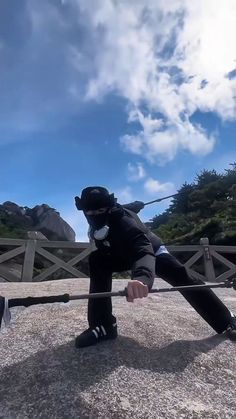 a man riding on the back of a skateboard down a cement road next to a wooden fence